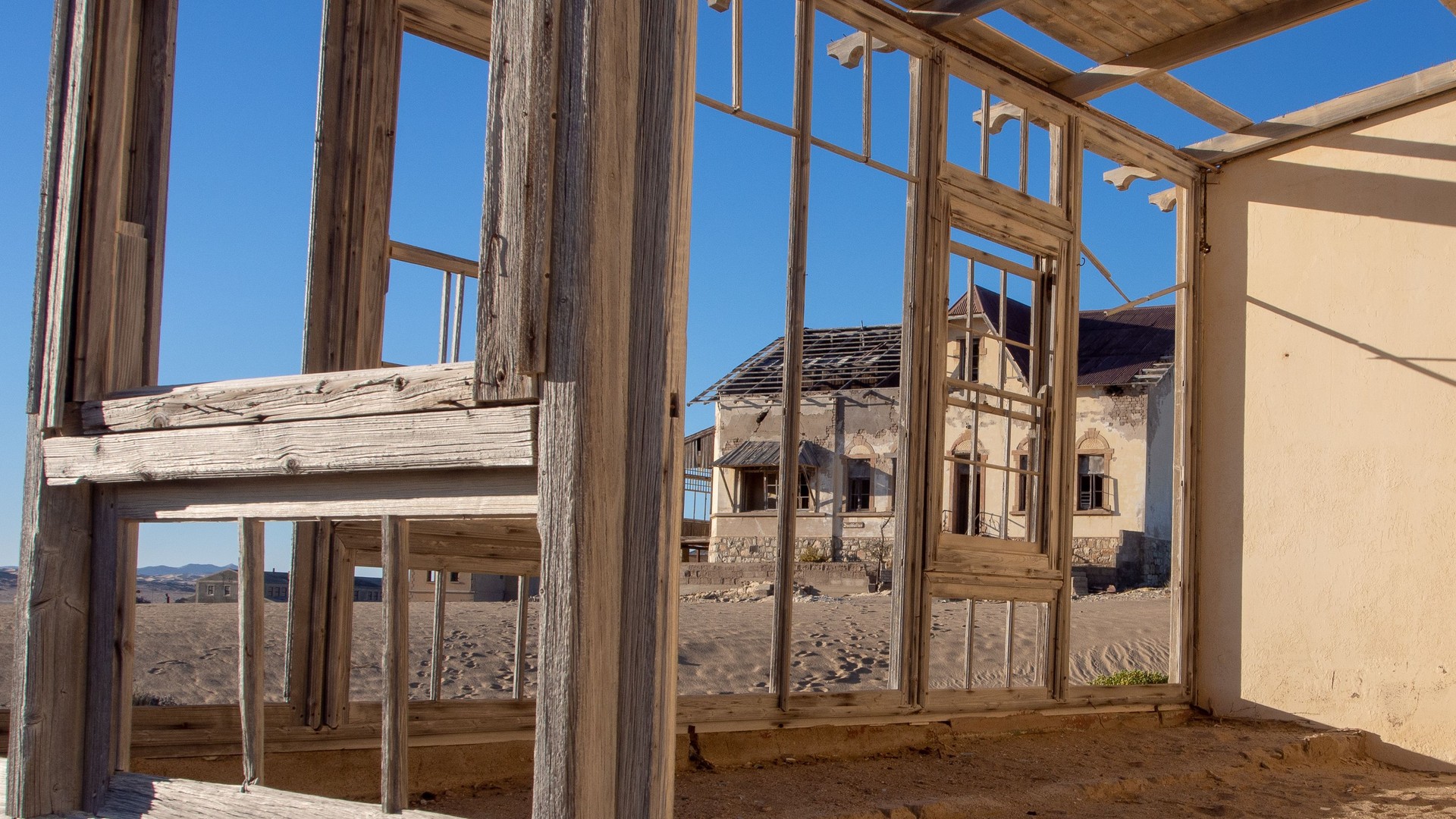 Vue à travers un cadre de fenêtre en bois de l’une des maisons négligées de la ville fantôme de Kolmanskop.